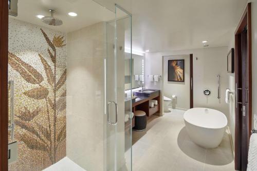 a bathroom with a tub and a glass shower stall at Hilton Grand Vacations Club Hokulani Waikiki Honolulu in Honolulu