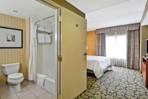 a bathroom with a toilet and a bed and a tub at Hilton Garden Inn Hattiesburg in Hattiesburg