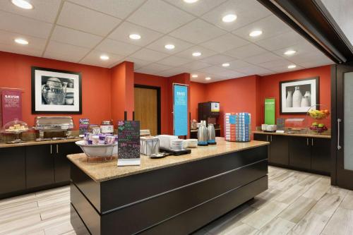 a restaurant with orange walls and a counter with food at Hampton Inn and Suites Houston Clear Lake NASA in Webster