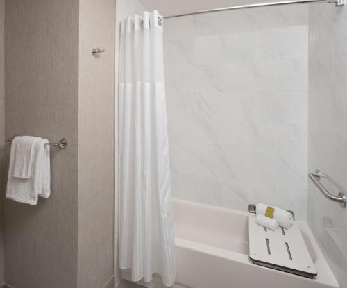 a bathroom with a shower with a white shower curtain at Hilton Houston North in Houston