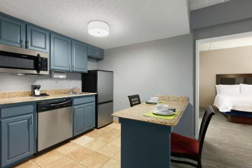 a kitchen with blue cabinets and a room with a bed at Hampton Inn and Suites Houston Clear Lake NASA in Webster