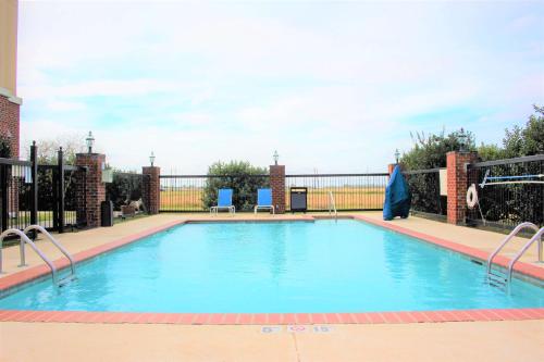 una gran piscina con 2 sillas azules. en Hampton Inn & Suites Thibodaux, en Thibodaux