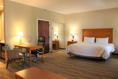 Habitación de hotel con cama grande y escritorio. en Hampton Inn & Suites Thibodaux, en Thibodaux