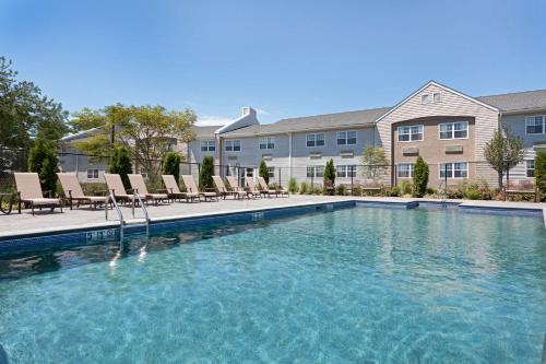 a large swimming pool with chairs in front of a building at DoubleTree by Hilton Cape Cod - Hyannis in Hyannis