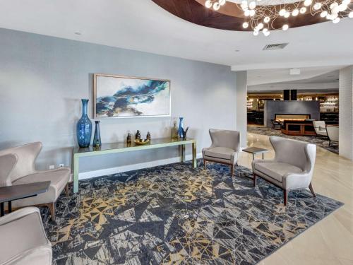 a living room with chairs and a table and a piano at DoubleTree by Hilton Wichita Airport in Wichita