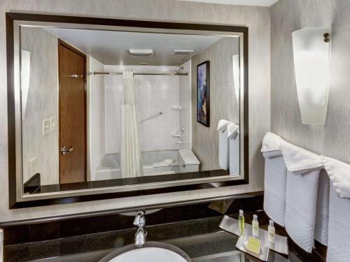 a bathroom with a large mirror above a sink at DoubleTree by Hilton Wichita Airport in Wichita