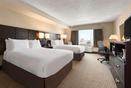 a hotel room with two beds and a desk at DoubleTree by Hilton Wichita Airport in Wichita