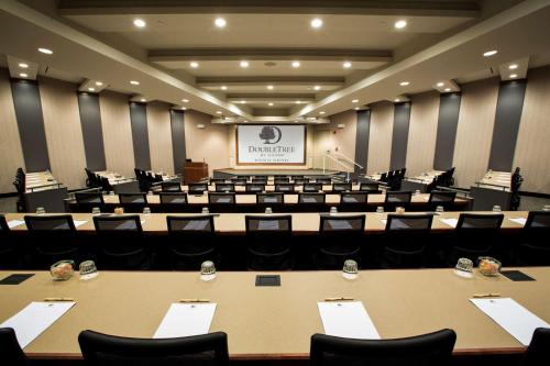 a conference room with tables and chairs and a screen at DoubleTree by Hilton Wichita Airport in Wichita