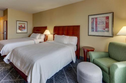 a hotel room with two beds and a chair at Hilton Garden Inn Indianapolis Airport in Plainfield