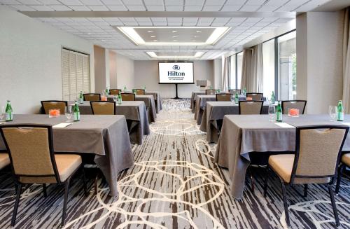 a dining room with tables and chairs and a screen at Hilton Houston Post Oak by the Galleria in Houston