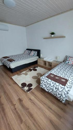 1 dormitorio con 2 camas y alfombra en el suelo en Anno Apartman, en Balatonföldvár