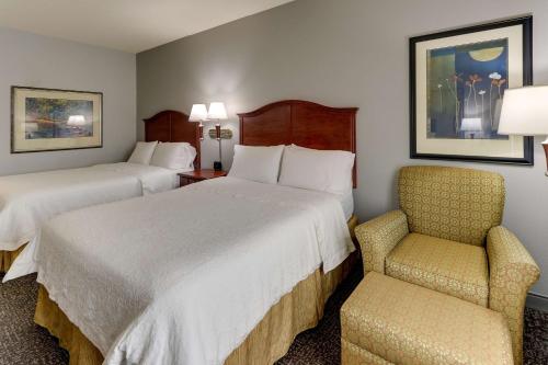 a hotel room with two beds and a chair at Hampton Inn & Suites Indianapolis-Airport in Indianapolis