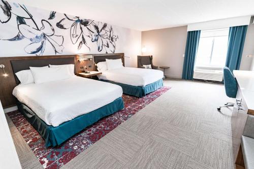 a hotel room with two beds and a desk at Hilton Garden Inn Fairfax in Fairfax