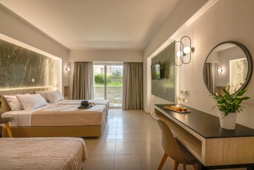 a hotel room with two beds and a desk with a mirror at Castro Beach Hotel in Maleme