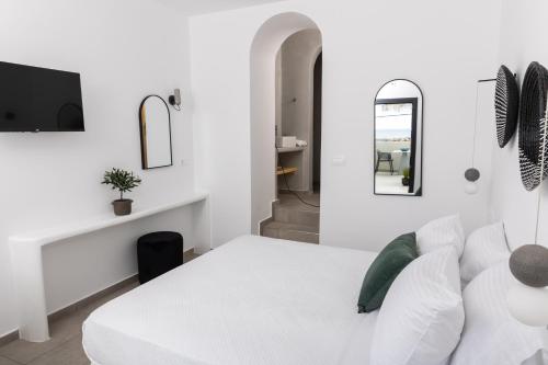 een witte slaapkamer met een wit bed en een spiegel bij Anafi Drops Mare in Anafi