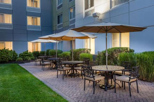 a group of tables with umbrellas in front of a building at Hilton Garden Inn Islip/MacArthur Airport in Ronkonkoma