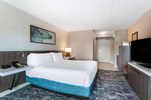a hotel room with a bed and a flat screen tv at Hilton Garden Inn Islip/MacArthur Airport in Ronkonkoma