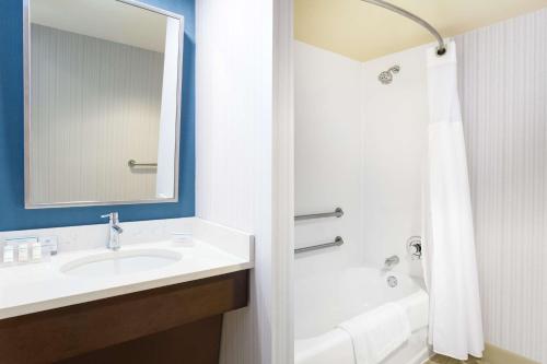 a bathroom with a sink and a tub and a mirror at Hilton Garden Inn Islip/MacArthur Airport in Ronkonkoma