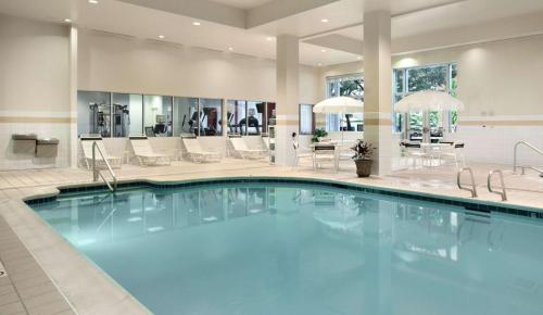 a pool in a hotel lobby with chairs and tables at Hilton Garden Inn Ithaca in Ithaca