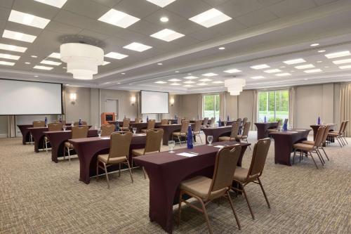 a conference room with tables and chairs and a projection screen at Hilton Garden Inn Stony Brook in Stony Brook