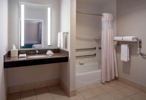 La salle de bains est pourvue d'un lavabo, d'une baignoire et d'une douche. dans l'établissement Hilton Garden Inn Jackson Downtown, à Jackson