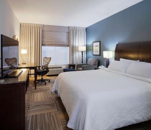 a hotel room with a large white bed and a desk at Hilton Garden Inn Jonesboro in Jonesboro