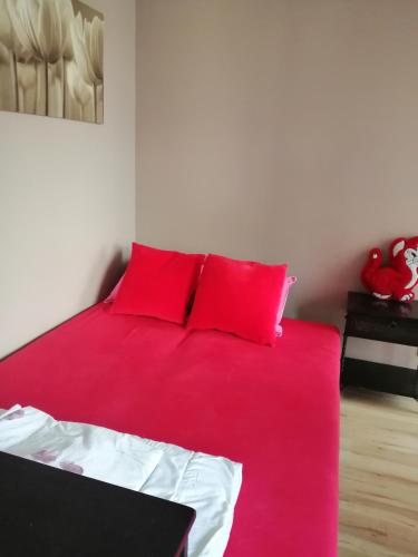 een rood bed met rode kussens in een kamer bij Kawalerka w centrum z parkingiem in Stargard