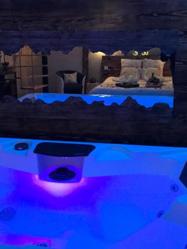 1 dormitorio con bañera y 1 cama con luces azules en Cosy Love & Spa Love room avec spa, hammam et sauna privatif en Cemboing