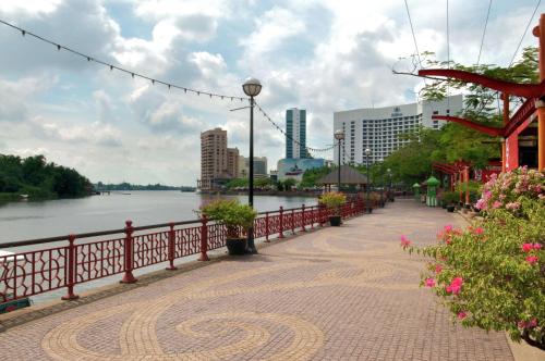 a brick walkway next to a river with buildings at Hilton Kuching Hotel in Kuching