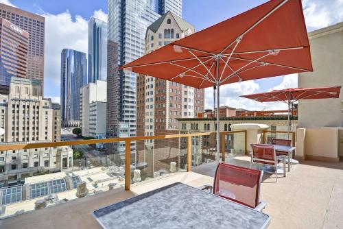 een balkon met een tafel, stoelen en parasols bij Hilton Checkers Los Angeles in Los Angeles