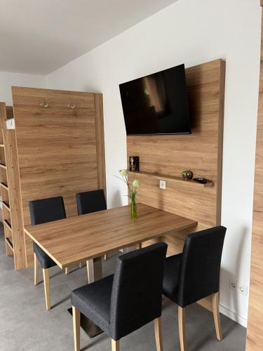 a wooden table with chairs and a television on a wall at Reiterhof Zwei Linden in Melle