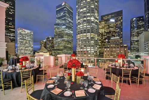 a group of tables on a rooftop with a city skyline at Hilton Checkers Los Angeles in Los Angeles