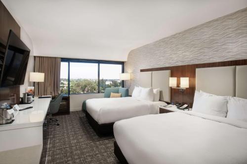 モンロビアにあるダブルツリー バイ ヒルトン モンロビア パサデナ エリアのベッド2台、薄型テレビが備わるホテルルームです。