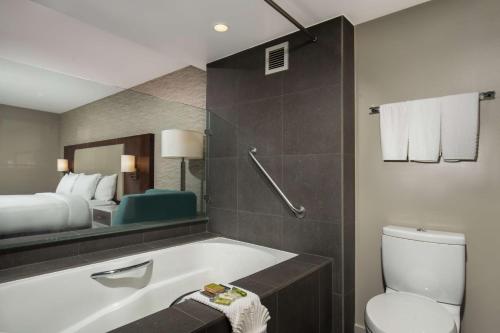 a bathroom with a tub and a bed and a toilet at DoubleTree by Hilton Monrovia - Pasadena Area in Monrovia