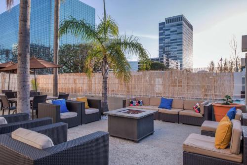 d'une terrasse avec des canapés, des tables et des palmiers. dans l'établissement DoubleTree by Hilton LAX - El Segundo, à El Segundo