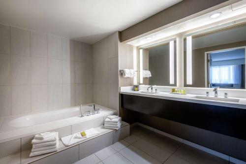 a bathroom with two sinks and a tub and a mirror at DoubleTree by Hilton Los Angeles Norwalk in Norwalk
