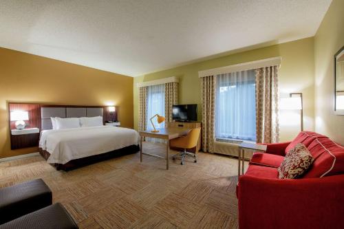 ラファイエットにあるHampton Inn and Suites Lafayetteのベッド、デスク、ソファが備わるホテルルームです。