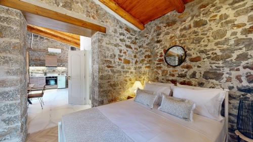 a bedroom with a bed in a stone wall at Petra Elounda Suites - Adults Only in Elounda