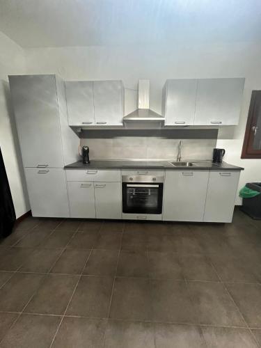 una cocina con armarios blancos y fregadero en Home Sarenji en Trivolzio