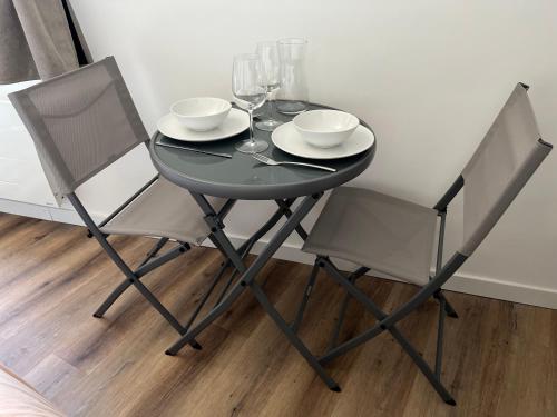 - une table noire avec 2 chaises et des verres à vin dans l'établissement Studio cocooning centre ville d'Honfleur, à Honfleur