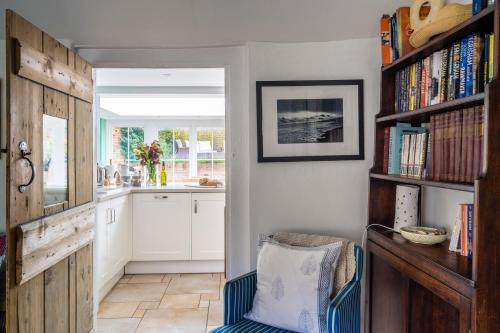 Myrtle Cottage في Friston: مطبخ مع كرسي ورف كتاب