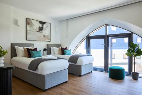 2 Betten in einem Zimmer mit einem großen Fenster in der Unterkunft Kew Bridge by Viridian Apartments in Kew Bridge