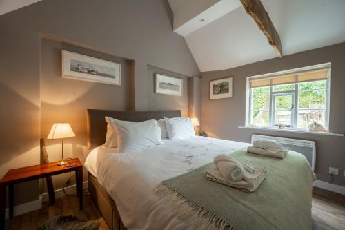 a bedroom with a bed with a towel on it at Myrtle Cottage in Friston