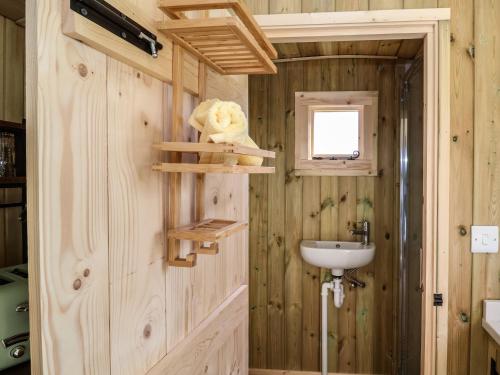 a bathroom with a wooden wall with a sink at The Oak Hut in Whitchurch