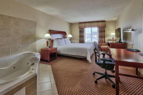 Habitación de hotel con cama, escritorio y bañera. en Hilton Garden Inn Las Cruces, en Las Cruces
