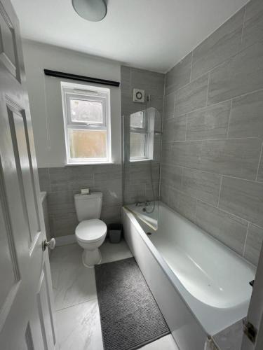 a bathroom with a toilet and a tub and a sink at House by Araminta in Hounslow