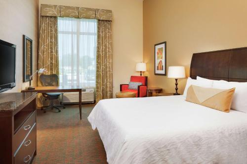 a hotel room with a bed and a desk and a television at Hilton Garden Inn Manhattan Kansas in Manhattan