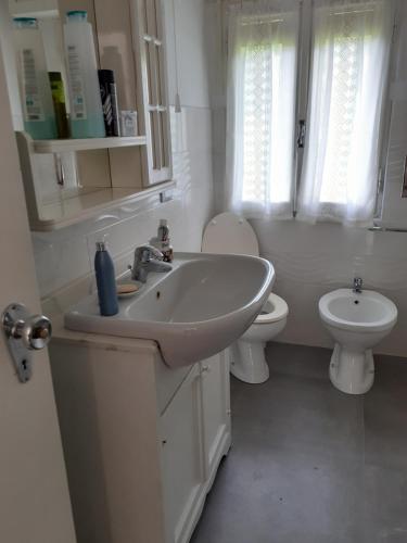 a white bathroom with a sink and a toilet at Appartamento Riolunato (MO) in Riolunato