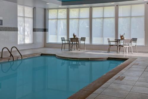 a pool in a room with chairs and a table at Hilton Garden Inn Kansas City/Kansas in Kansas City