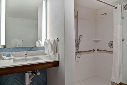 La salle de bains est pourvue d'un lavabo et d'une douche. dans l'établissement Hilton Garden Inn Kansas City/Kansas, à Kansas City